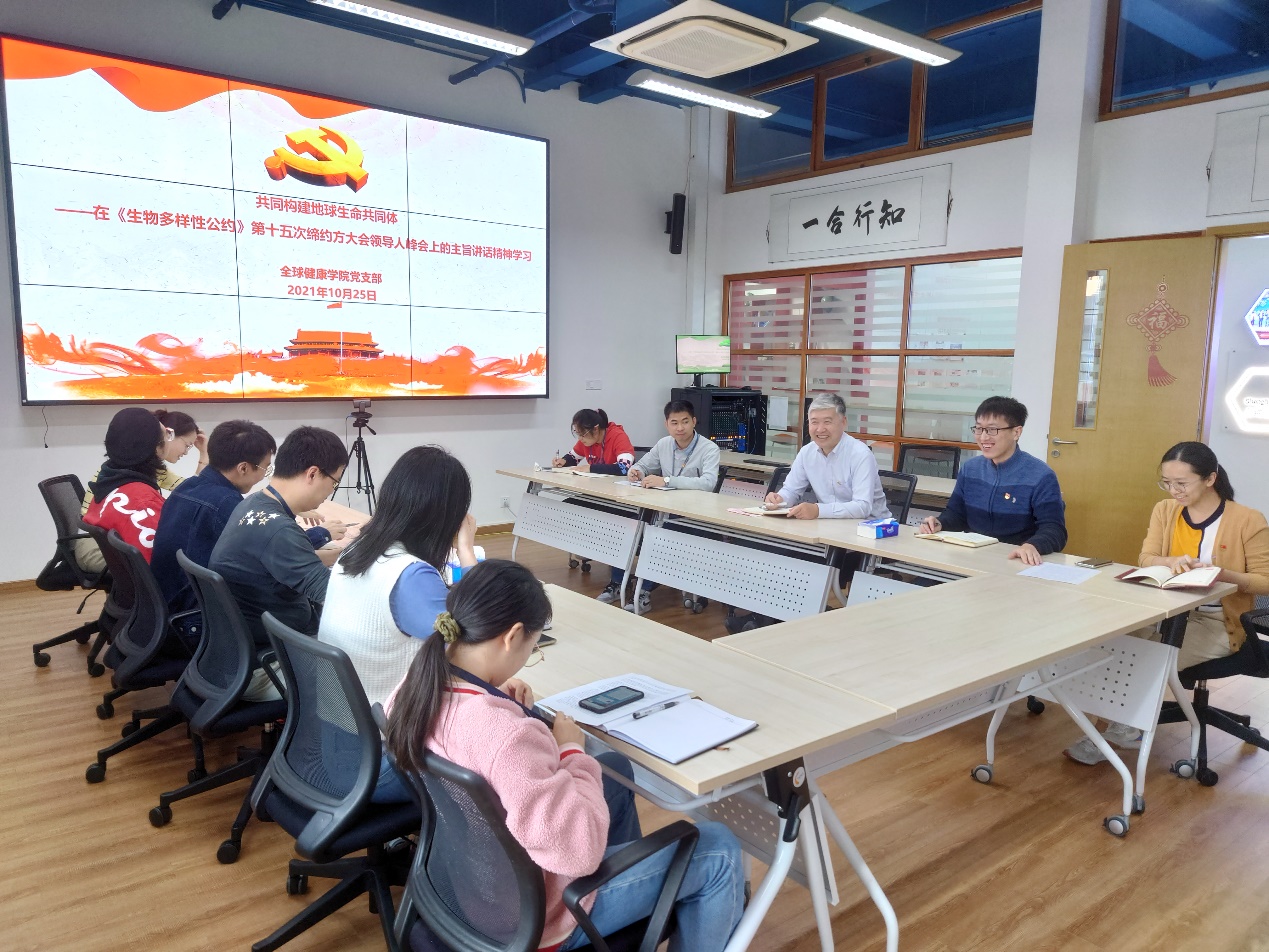 A group of people sitting at a table looking at a screenDescription automatically generated with low confidence